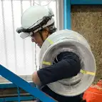 電線リールを担いで階段を移動する電気工事士